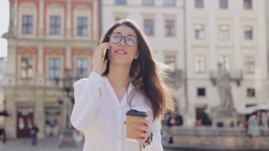 Akıllı telefondan konuşan ve dışarıda kahve içen çekici genç bir kadın portresi. Bulanık geçmişiyle akşam caddesinde arama yaparken cep telefonu kullanan güzel beyaz bir kız.