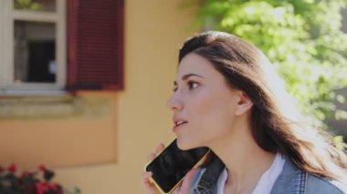 Duygular. Esmer, beyaz bir kadının en iyi arkadaşını telefonla aramasının ve yaz caddesinde arkadaşça sohbet etmesinin portre görüntüsü.