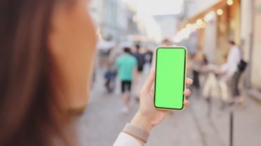 Açık havada telefon yeşil ekranı kullanan bir kız. Eller iş telefonlarını modern ekranda tutuyor ve kameraya gösteriyor. CHROME Anahtarı Konsepti