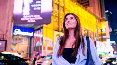 Geceleri neon ışıklarla modern şehrin sokaklarında yürüyen büyüleyici güzel bir kadının portresi. Çekici, heyecanlı, gülümseyen genç bir kadın. Şehir sinemasında olmaktan mutlu..