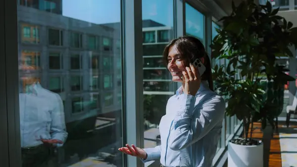 Successful female person calling by cell phone in big company building. Business and big company concept.