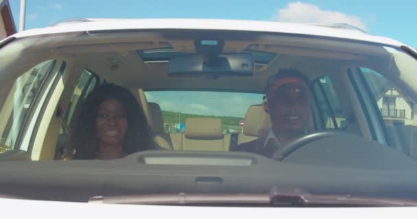 車に座っている幸せな愛するアフロマリカのカップルのフロントビュー 少女はリズムで動いています 一緒に楽しんでいる若者たち 男は運転して女の子と話している いい気分だった 楽しかった 車のインテリア — ストック動画