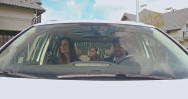 Macera zamanı. Eşi ve kızıyla birlikte arabaya binerken sıradan giyinmiş, yola bakan çekici bir genç adamın ön görüntüsü. Arka planda müzik dinleyen kız