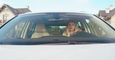 Kafkasyalı mutlu bir kadın yolda araba sürüyor ve telefonla konuşuyor. Arabaların içi. Ön görünüm.
