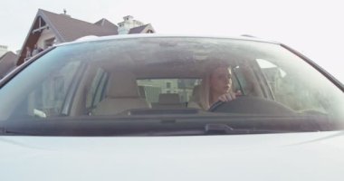 Kafkasyalı mutlu bir kadın yolda araba sürüyor ve araba oyununda konuşuyor. Arabaların içi. Ön görünüm.