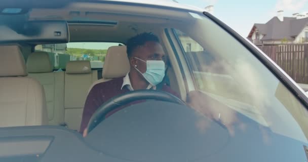 Πολυφυλετικός Άντρας Που Φοράει Προστατευτική Μάσκα Κάθεται Πίσω Από Τιμόνι — Αρχείο Βίντεο