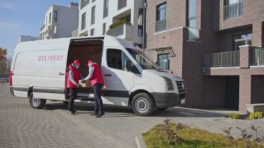 Afrika kökenli Amerikan kuryesi, beyaz maskeli ve eldivenli kuryeye bir paket kutusu veriyor. Posta paketini bir müşteriye teslim etmeye giden teslimatçı..