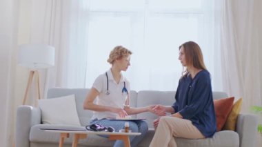 Ev ziyareti sırasında kızıl ötesi temas olmayan termometre kullanarak hastalarının sıcaklığını ölçen kendinden emin bir kadın aile doktoru.