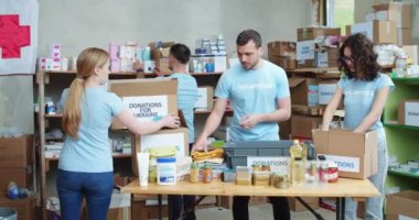 Mavi üniformalı genç beyazlar, Ukraynalılar için kutularda mal paketlemek için yardım fonunda gönüllü olarak çalışıyorlar. Destek, dayanışma ve insani yardım kavramı.