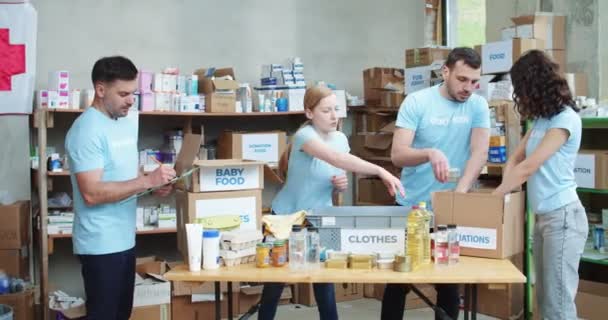 Elinde Dosya Olan Yakışıklı Genç Adam Bağış Kutularının Paketleme Sürecini — Stok video