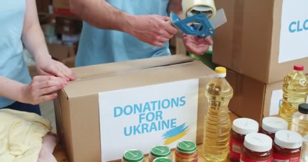 우크라이나 사람들을위한 기부와 마분지 상자를 포장하고 테이핑 봉사자의 러시아와의 우크라이나를 — 비디오