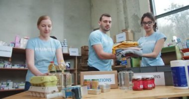 Yiyecek bankasında karton kutular paketleyen bir grup konsantre gönüllü. Yardıma ihtiyacı olan insanlara bağış dağıtan yardımsever gençler..