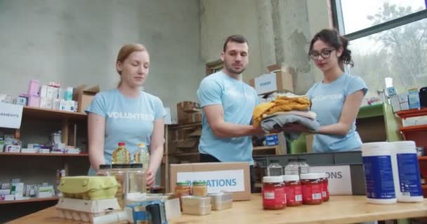 Equipo Joven Camisetas Azules Empacando Comida Donando Ropa Cajas Almacén — Vídeo de stock