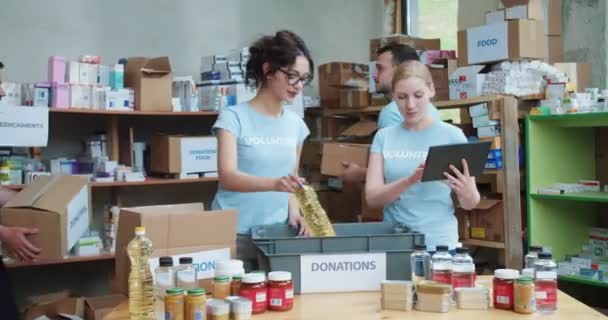 Female Food Bank Worker Typing Digital Tablet While Her Colleague — Stock Video