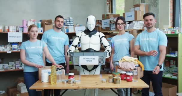 Ομάδα Εθελοντών Μπλε Στολή Ποζάρουν Σταυρωμένα Χέρια Ενώ Ανθρωποειδές Ρομπότ — Αρχείο Βίντεο