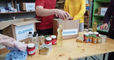 İnsanların ellerinin içinde yiyecek ve giyecek olan karton kutuları bağış fonuna koymasını engelle. Genç gönüllülerden oluşan bir ekip bağış etkinliği sırasında ihtiyacı olanlara yardım organize ediyor..