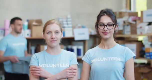 Retrato Dos Voluntarias Uniforme Azul Posando Con Brazos Cruzados Almacén — Vídeo de stock
