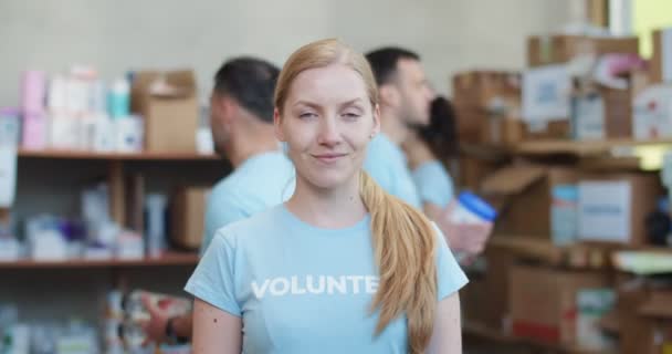 在食品库仓库摆姿势时 微笑的女性志愿者看着相机的肖像 吸引女性在慈善基金工作时帮助有需要的人 — 图库视频影像