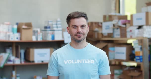 身穿蓝色志愿T恤 留着胡子的高加索男子站在食品库仓库时 在镜头前面带微笑的画像 捐赠和慈善概念 — 图库视频影像