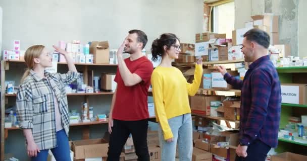 Fiatal Örömteli Emberek Pacsit Adnak Egymásnak Miközben Önkénteskednek Adományozó Központban — Stock videók