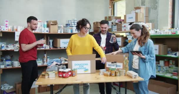 Ενεργή Ομάδα Νεαρών Εστιασμένων Εθελοντών Που Συλλέγουν Δωρεές Τροφίμων Χαρτόκουτα — Αρχείο Βίντεο