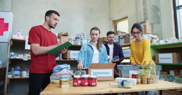 Tým Mladých Dobrovolníků Třídí Dary Plastových Lepenkových Krabicích Skladu Mladý — Stock video