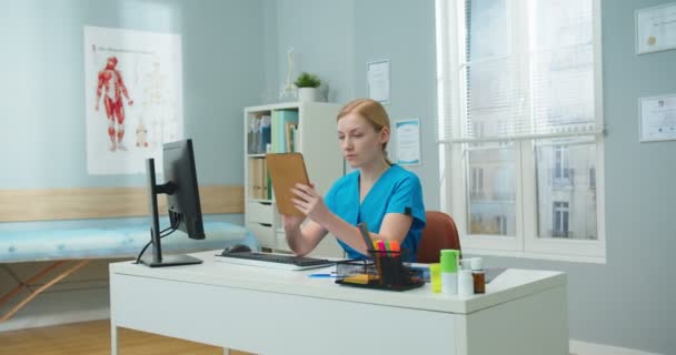 Atraktivní Běloška Modré Lékařské Uniformě Sedící Stolu Ordinaci Lékařů Mladá — Stock video