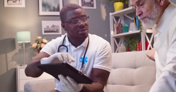 Zbliżenie Młody Afroamerykanin Profesjonalny Lekarz Specjalista Rozmawiający Kaukaski Stary Pacjent — Wideo stockowe