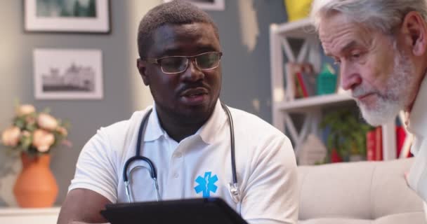 Młody Afroamerykanin Profesjonalny Męski Lekarz Specjalista Rozmawia Białym Starym Pacjentem — Wideo stockowe