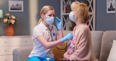 Kafkasyalı genç kadın sağlık uzmanı doktor portresi. Eski bir hastayı muayene ediyor. Coronavirus karantinası sırasında steteskop kullanıyor.