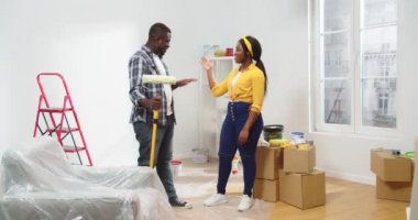 Mutlu Afro-Amerikan genç çift pozitif karı koca yeni apartman dairesinde dikiliyorlar. Keyifleri yerinde. Kameraya bakıp gülümsüyorlar.