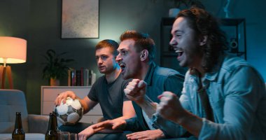 Gergin beyaz erkek futbol fanatikleri TV izlerken ve gece geç saatlere kadar oturma odasında otururken favori takım için bağırıyor, endişeleniyor ve tezahürat yapıyorlar. Erkek arkadaşlar güzel bir akşam geçiriyorlar..
