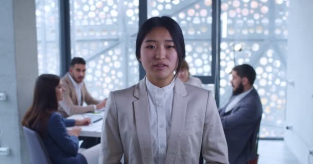 若い美しいアジアの女性 会社の労働者は ビジネス上のビデオロギングのようなカメラに何かを言う 背景についてのミーティング 金融ビデオブロガーが話し 説明しています 女性のオンラインコーチ — ストック動画