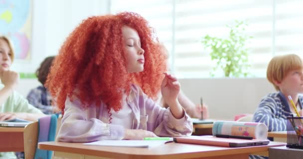 可爱的小聪明女学生的画像 红头发 坐在课桌前 举手作答 在孩子们中间里面 小女孩在学校学习 — 图库视频影像