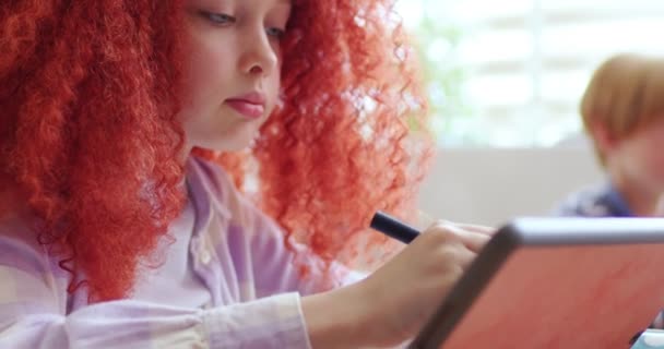 认真的女学生 在教室的数码平板电脑上写着红色卷曲的发式 冷静聪明的女生 看着黑板 在学校上课时注意运动 — 图库视频影像