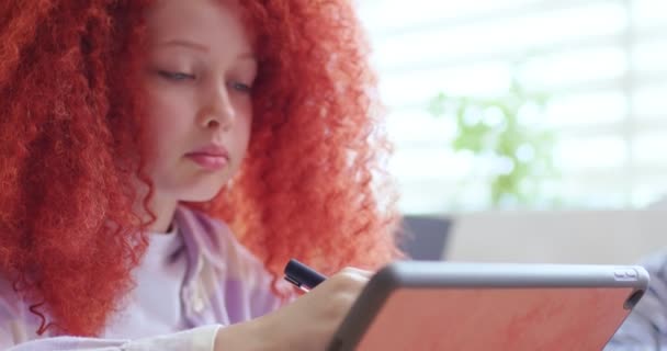 关闭聪明的女生与红色卷发坐在课堂上 并使用平板设备上课 聪明的小女孩在学校学习 敲敲电脑屏幕 交互式研究 — 图库视频影像