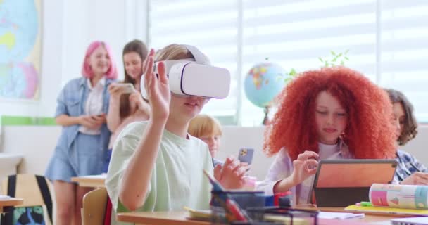 戴Vr耳机的白人小男孩坐在教室的课桌前 具有虚拟现实的学习经验 互动学习概念 戴Vr眼镜的男中学生手牵手 — 图库视频影像