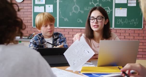 Kaukasischer Junger Lehrer Sitzt Mit Kleinen Intelligenten Schülern Schreibtisch Und — Stockvideo