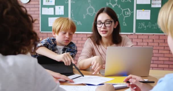 Νεαρή Δασκάλα Κάθεται Στο Γραφείο Μαζί Μικρούς Έφηβους Έξυπνους Μαθητές — Αρχείο Βίντεο