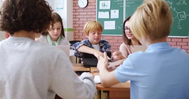 白人快乐的孩子与年轻的女教师一起坐在办公桌前学习 做家庭作业或玩耍 学校班级的概念 插话式学习 与主人交谈的孩子 — 图库视频影像