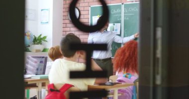 Modern okulda kalifiye erkek öğretmenin yönettiği kapalı kimya dersine bakın. Öğrenciler masalarında çeşitli aletlerle oturuyorlar. Teknoloji ve eğitim kavramı.