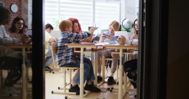 Вид Двери Класса Кавказских Детей Подростков Сидящих Столом Учащихся Вместе — стоковое видео
