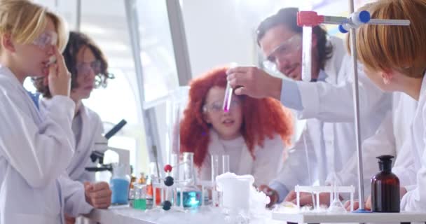 照相机把镜头对准了在学校化学实验室做实验的戴眼镜的孩子和他们的男老师 化学课 熟能生巧 — 图库视频影像