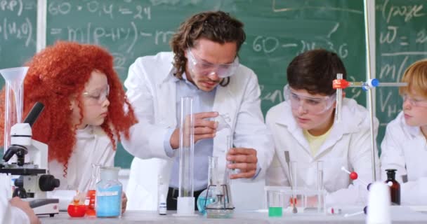 Geconcentreerde Leerlingen Met Een Jonge Mannelijke Leraar Die Chemisch Experimenteert — Stockvideo