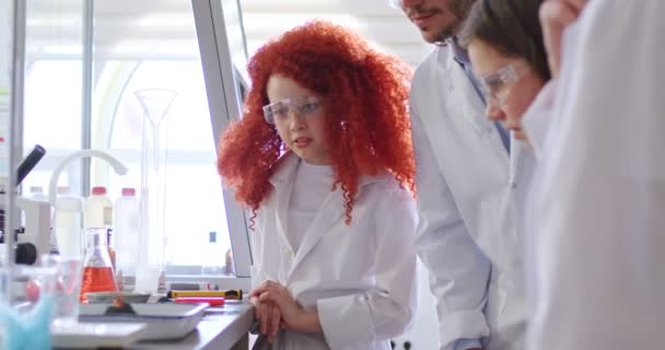 热心的高加索教师在课堂上与学生一起做化学实验 专注于穿着眼镜和实验室外套的好奇漂亮的红头发女学生 — 图库视频影像