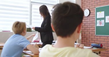 Beyaz, genç, biyoloji öğretmeni. Öğrencilere sınav kağıtları dağıtıyor. Okuldaki sınavlar. İnceleme konsepti. Sınıftaki çocuklar için biyoloji ya da kimya testi. Eğitim.