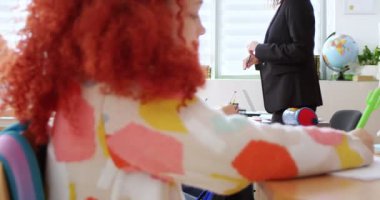 Masalarda oturan ve sınav yazan çocukları kapatın. Kafkasyalı katı bayan öğretmen, çocukları okulda testten geçerken izliyor. Kontrol konseptini çalış. Öğrenciler ustanın kontrolü altında. Sınıfta sınav.