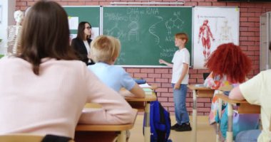 Sınıfta tahtaya yakın durup DNA yapısıyla ilgili sorulara cevap veren kızıl saçlı tatlı bir çocuk. Bayan öğretmen yakın zamanda cevap verecek, sınıf arkadaşları masalarında oturacak. Biyoloji dersi.