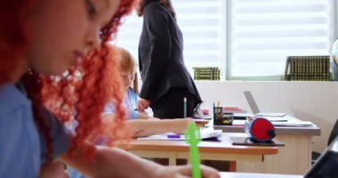 Beyaz kadın biyoloji öğretmeni. Öğrencilerden sınav kağıtları alıp topluyorlar. Okuldaki sınavlar. İnceleme konsepti. Sınıftaki çocuklar için biyoloji ya da kimya testi. Eğitim.