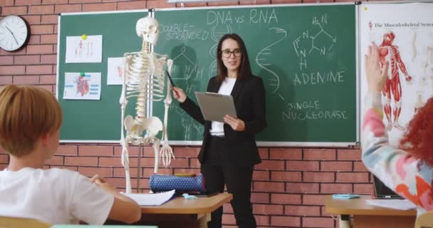 美丽的高加索年轻女解剖学或生物学教师向学生解释人体和骨骼的小球模型 在学校教育概念 有趣的知识 — 图库视频影像